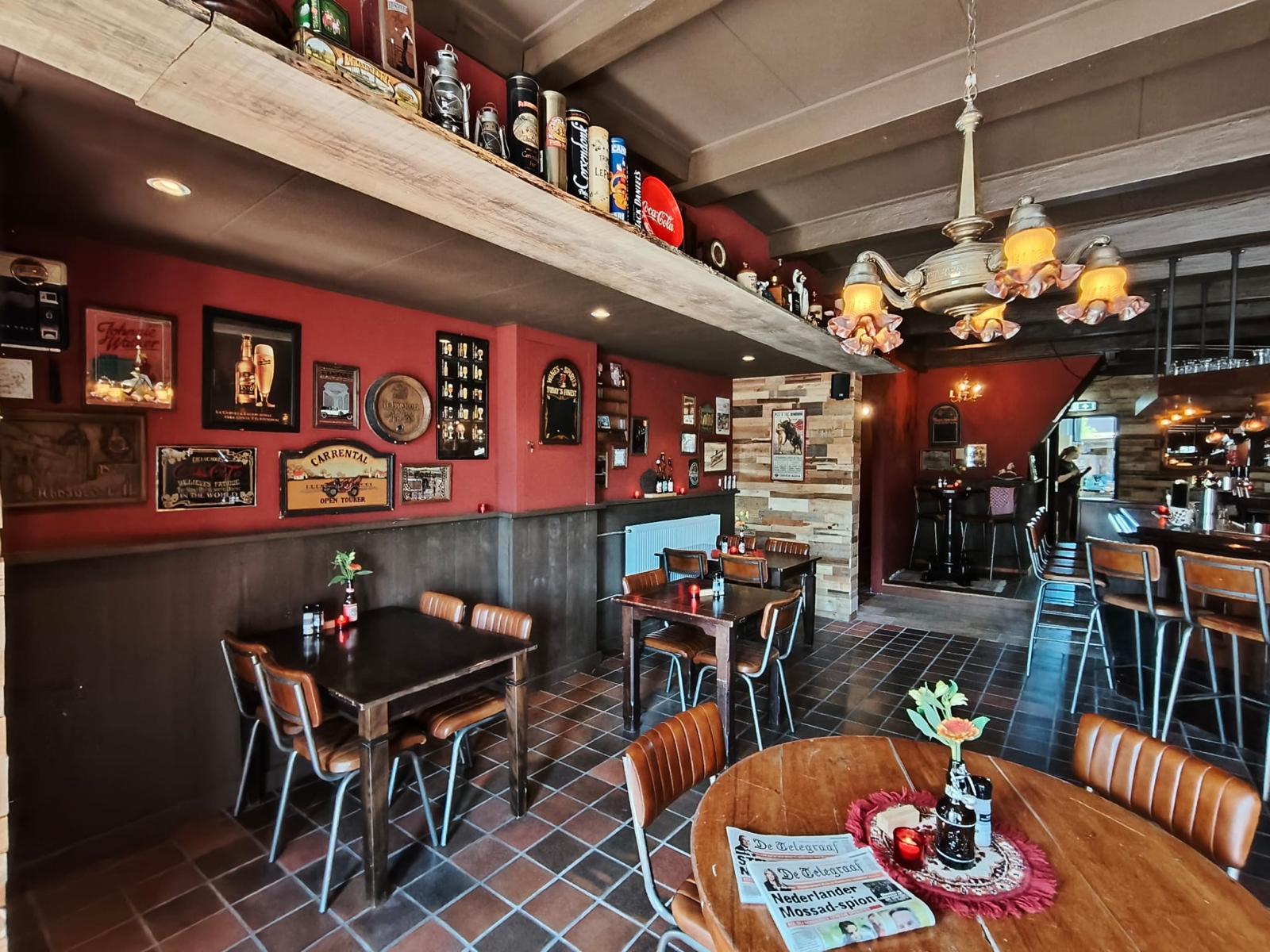 Interieur van restaurant Balk — Eetcafé De Dames: warme verlichting, bordeauxrode wanden en vintage decoratie